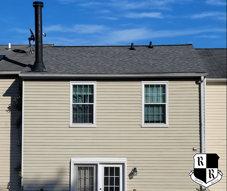 Rooftop with red shingles and a dark repair patch in the center, a wooden square patch nearby, two green vent caps, and a company logo in the bottom-left corner.