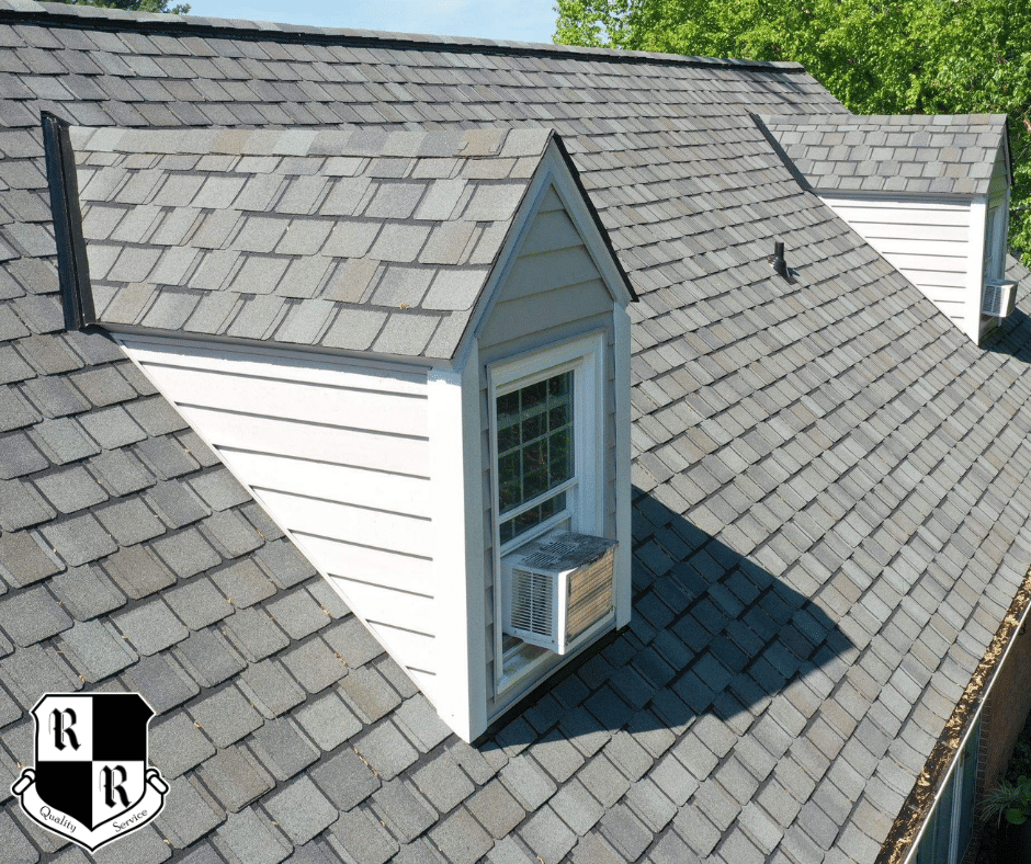 On a red shingled roof, a white vent boot is installed with a hammer, pry bar, and pliers nearby; worker's shoes visible at bottom.